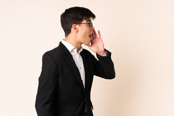 Businessman over isolated beige background shouting with mouth wide open