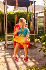 Little boy going to sleep on a swing in beautiful summer garden