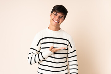 Obraz premium Handsome man over isolated beige background presenting an idea while looking smiling towards