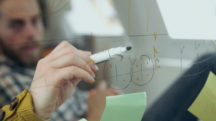 Good-looking serious bearded guy drawing marks on glass wall in office room to see vision of further business strategy,4k