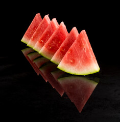 Pieces of watermelon in a black tray on a black background