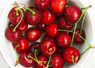 A lot of fresh sweet cherry fruit berries with water drops, close up. Pile of ripe cherries. Large collection of fresh red cherries. Ripe cherries texture background