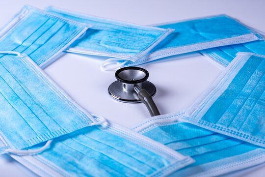 Closeup of a stethoscope surrounded by facemasks in a heart shape on the table - COVID-19