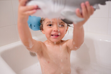 Boy playing in bath with toys 