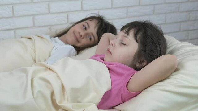 Sisters in the bed. Cute little girls in the morning lie in bed.