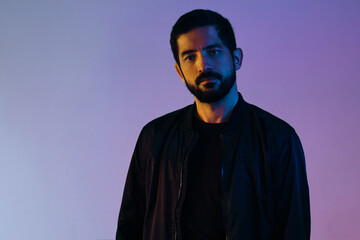 Dramatic portrait of man wearing jacket lit by blue and red lights.