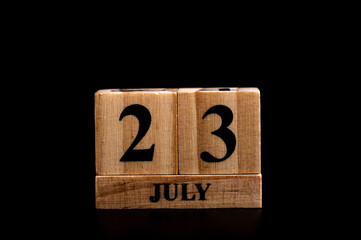 wooden calendar 23 July word on black background with copy space , selective focus at the calendar