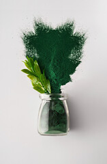 Spirulina Chlorella algae powder in a glass jar and in a spoon on a white background. Vertical...