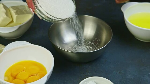 slow motion closeup female hands pour white sugar into small empty metal bowl