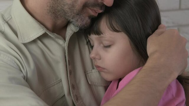 Sleep in father's arms. The sweet little girl fell asleep in her mother's arms.
