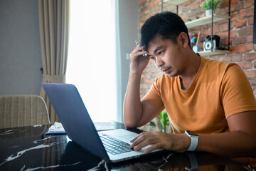 Asian man uses a notebook computer and works hard and meeting at home and he is stressed and Headache.