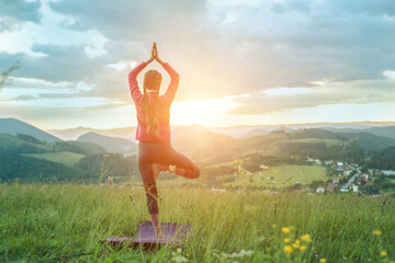 Yoga in nature, fresh air in park. Sporty girl practicing pose, stretching health on top of mountain in meadow at sunrise, zen wellness. Teamwork, good mood and healty life.