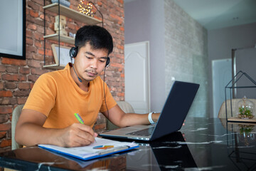 Fototapeta premium Asian businessmen is using notebook computers and wear headphones for online meetings and working from home.