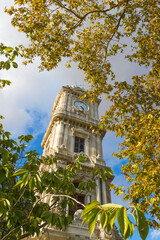 Obraz premium Clock Tower in the frame of bright fall foliage. Is a clock tower situated outside Dolmabahce Palace in Istanbul, Turkey. Built in 1895