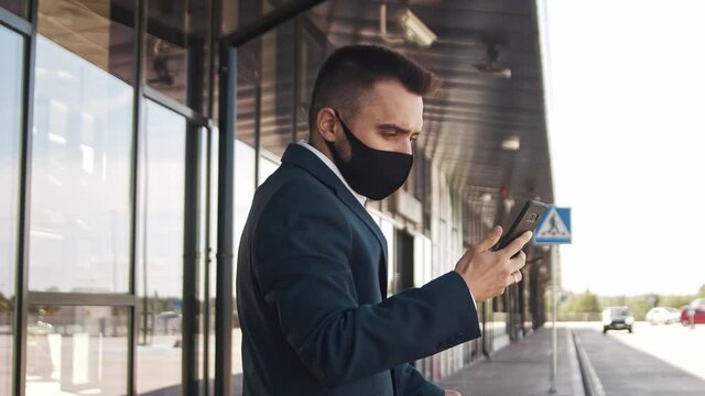 Elegant businessman wearing protective mask in airport. Young mail entrepreneur in formalwear. Pandemic, new rules of control, business trip and traveling.