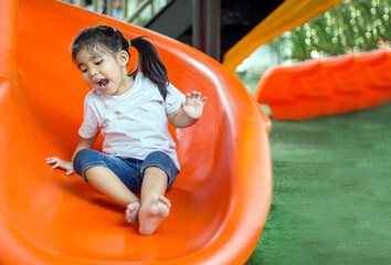 Fototapeta na wymiar asian Thai girl smile and fun with slider outdoor playground
