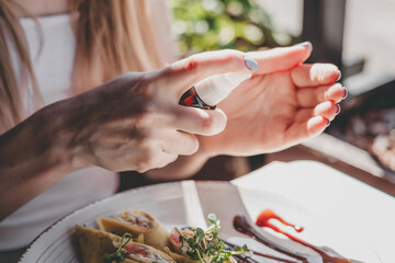 Female hands use an antiseptic to clean hands during a coronavirus pandemic, city cafe, close up