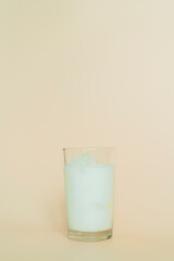 베이지색 배경에서 촬영한 얼음 우유 유리컵
