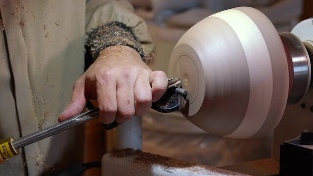 Craftsman works with workpiece in authentic workshop. Woodworker handles wood by bench. Making beautiful wooden handmade dish. Creation of unusual plate. Carpenter cuts wood by graver in soft focus