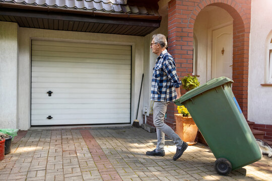 Senior Man Rolling Garbage Can
