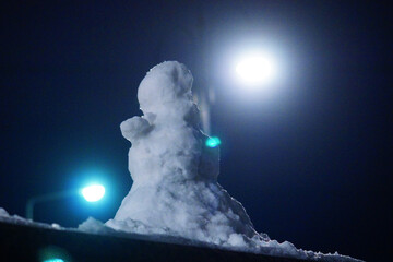 Cute little snowman alone in the late evening.