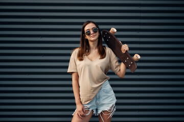Young Woman With Longboard. Girl skater posing on longboard in sunny weather © glazunoff