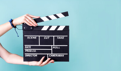 Female hands holding a clapper board isolated on blue