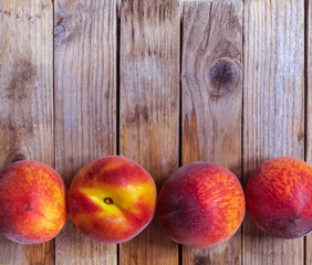 View from above on four juicy peaches that lie on a wooden table