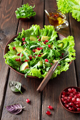 Avocado and pomegranate salad in a clay plate on a wooden background. Healthy food.