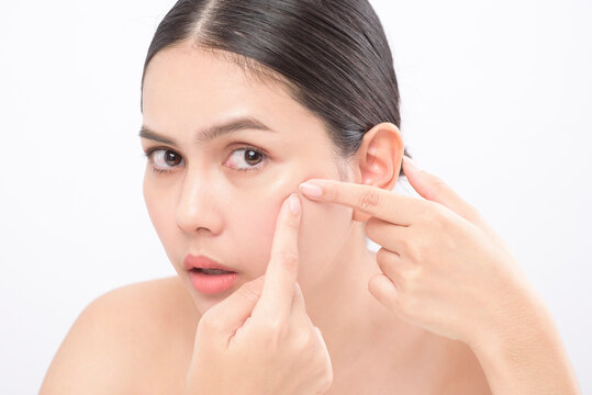 portrait of young beautiful woman is checking her skin and popping pimple over white background studio