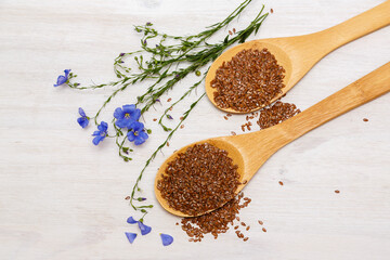 Flax seeds and a blue flower of flax on a wooden background. Healthy food and drink concept. Flax seeds is a superfood