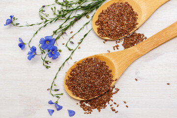 Flax seeds and a blue flower of flax on a wooden background. Healthy food and drink concept. Flax seeds is a superfood