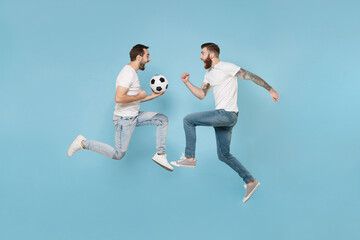 Fototapeta na wymiar Side view of screaming men guys friends in white t-shirt isolated on pastel blue background. Sport leisure lifestyle concept. Cheer up support favorite team with soccer ball jump doing winner gesture.