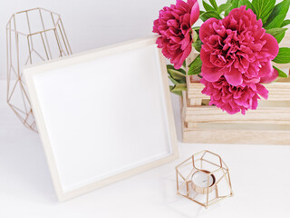 Flower composition. Empty wooden photo frame decorated with lush red peonies. Copy space.