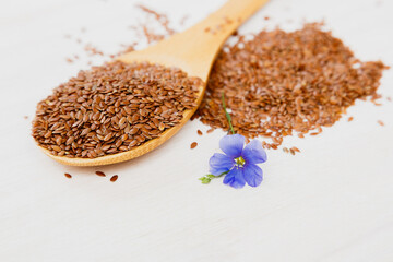 Flax seeds and a blue flower of flax on a wooden background. Healthy food and drink concept. Flax seeds is a superfood