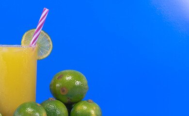 Glass of fresh lemonade and fruits on blue background