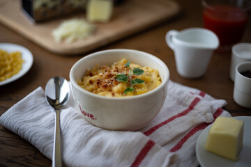 Homemade Baked Mac and Cheese on a Wooden Table with Ingredients Placed Around it.