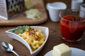 Homemade Baked Mac and Cheese on a Wooden Table with Ingredients Placed Around it.