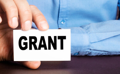 A man holds a business card with the written word GRANT
