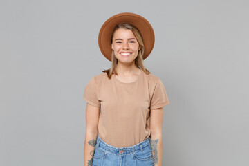 Smiling beautiful young blonde woman girl in casual beige t-shirt hat posing isolated on gray background studio portrait. People sincere emotions lifestyle concept. Mock up copy space. Looking camera.