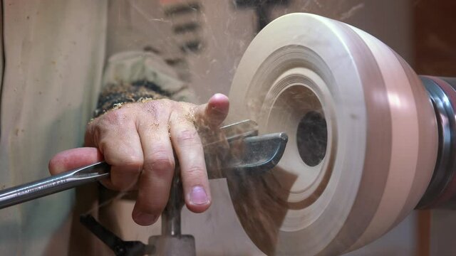 Craftsman works with workpiece in authentic workshop. Woodworker handles wood by bench. Making beautiful wooden handmade dish. Creation of unusual plate. Carpenter cuts wood by graver in soft focus