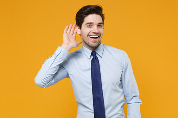 Curious young business man in classic blue shirt tie isolated on yellow background studio....