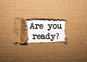 The text ARE YOU READY. behind torn brown paper