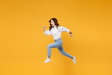 Fototapeta na wymiar Side view of shocked young brunette business woman in white shirt posing isolated on yellow background in studio. Achievement career wealth business concept. Mock up copy space. Jumping like running.