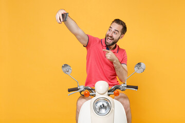 Excited young bearded man guy in casual summer clothes driving moped isolated on yellow background....