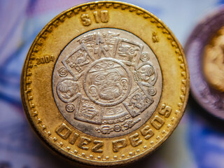 Closeup view of Mexican coins (10 pesos) with bank note as a background. Selective focus