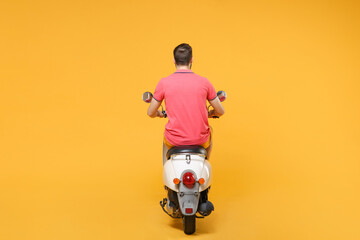Back rear view of young man guy in casual summer clothes driving moped isolated on yellow wall...