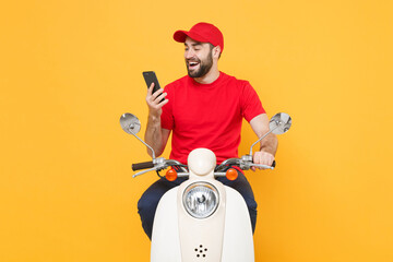Delivery man in red cap t-shirt uniform driving moped motorbike scooter hold mobile phone isolated...