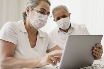 Obraz premium The elderly couple trying to use the tablet show each other something on the screen. old couple is trying to talk to their grandchildren. old couple is trying to talk to their children.