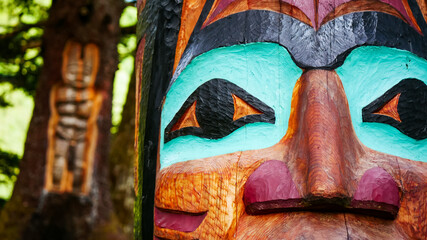 Closeup of colorful Alaskan totem pole in a forest in Juneau and Native art carving on live tree...